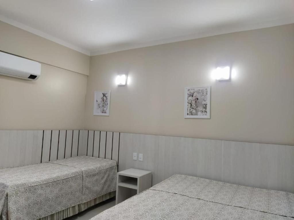 een slaapkamer met 2 bedden en 2 verlichting aan de muur bij Spazzio diRoma in Caldas Novas