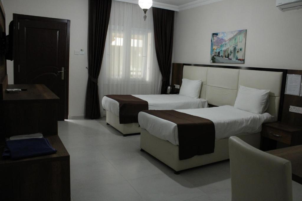 a hotel room with two beds and a desk at En Kaya Hotel in Lefkosa Turk