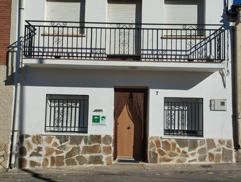 un pequeño edificio blanco con balcón y puerta en Casa Rural "La Muela de Alarilla" 