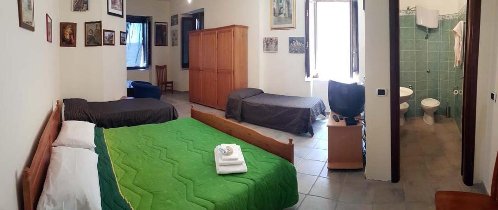 1 dormitorio con cama verde y baño en B&B Gioiosa e Delia, en Gioiosa Ionica