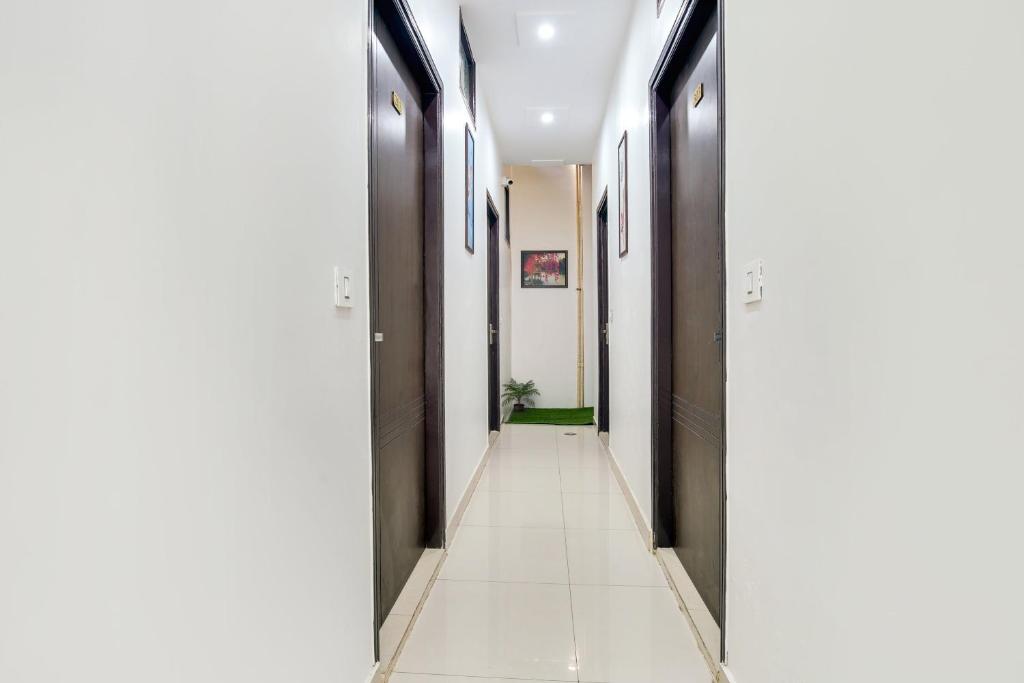 un pasillo con baldosas blancas, paredes negras y suelo blanco en Super OYO Flagship King Star Residency, en Bathinda