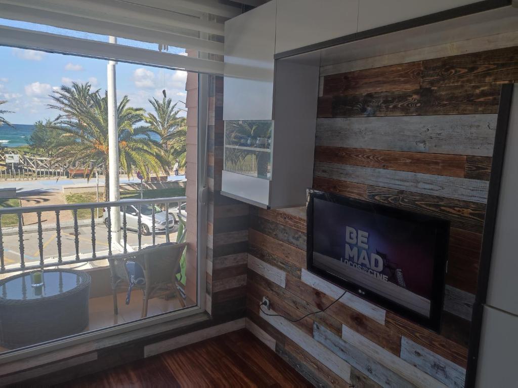 sala de estar con TV y vistas a la playa en APARTAMENTO EN LINEA DE PLAYA, en Suances