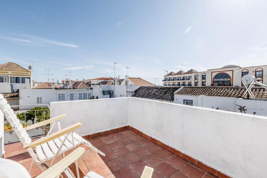 a balcony with two chairs and a view of the city at Casa Delgado in Tavira