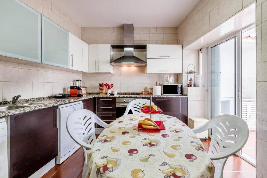a kitchen with a table and chairs and a kitchen with white cabinets at Casa Delgado in Tavira