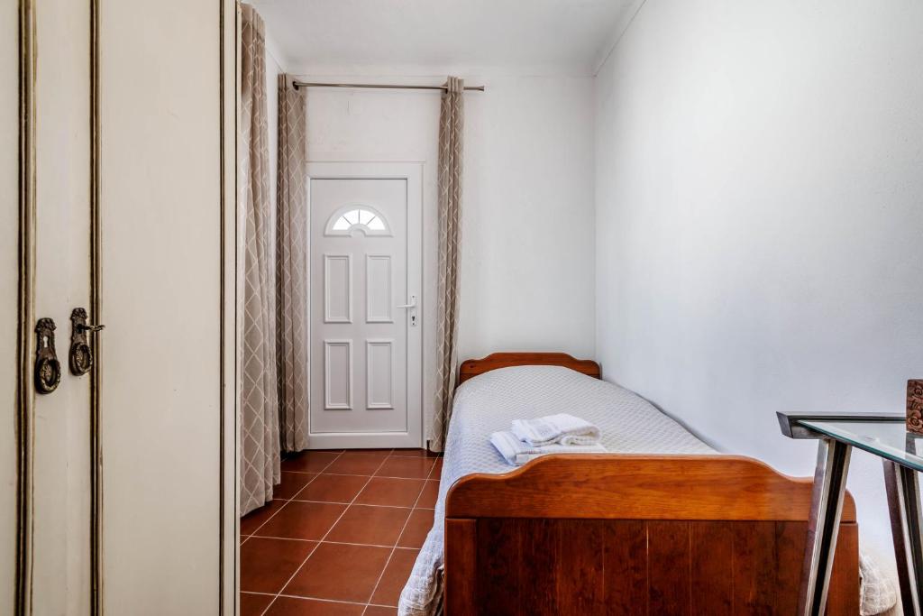 a small bedroom with a bed and a door at Casa Delgado in Tavira
