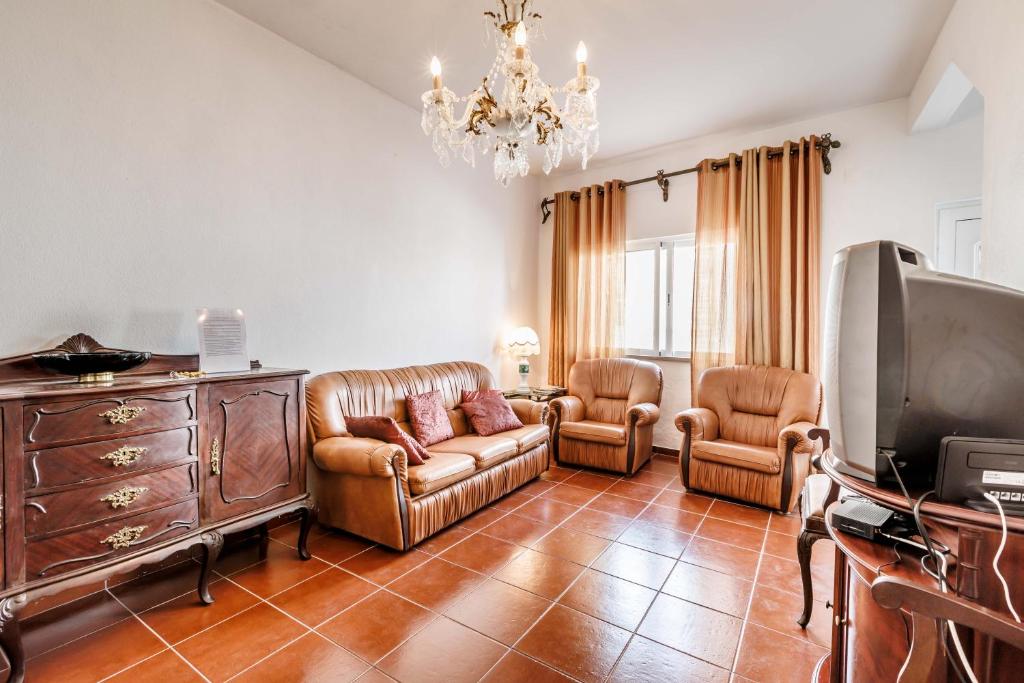 a living room with a couch and chairs and a tv at Casa Delgado in Tavira