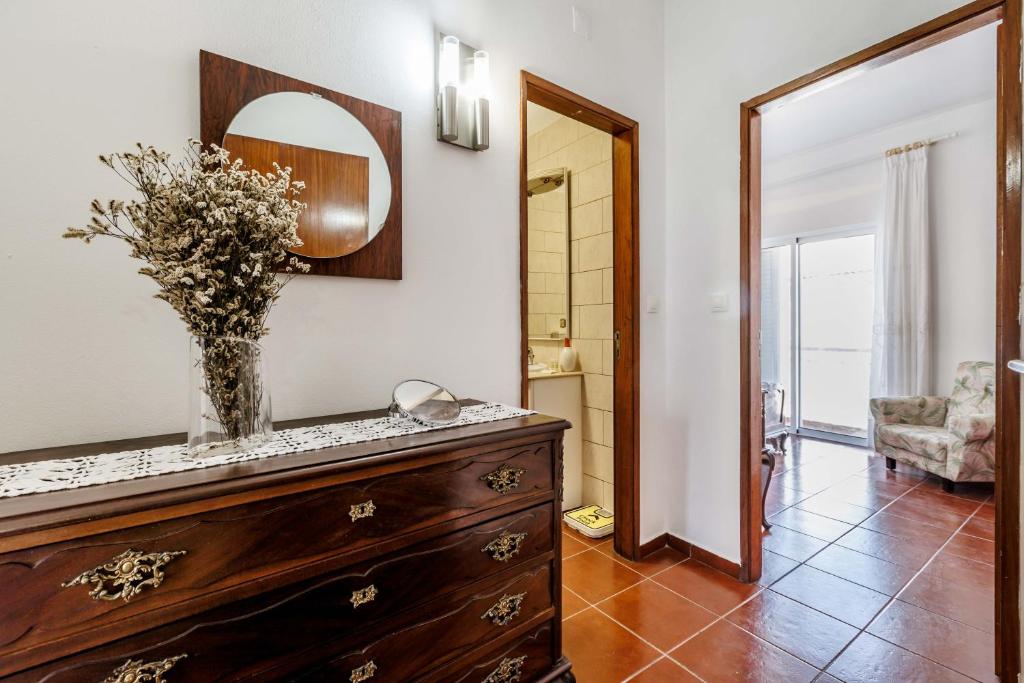 a room with a dresser with a vase of flowers on it at Casa Delgado in Tavira