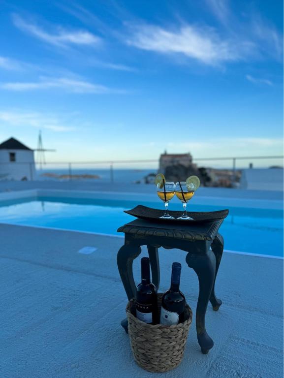 a table with two glasses and a basket of wine bottles at O Mylos in Ermoupoli