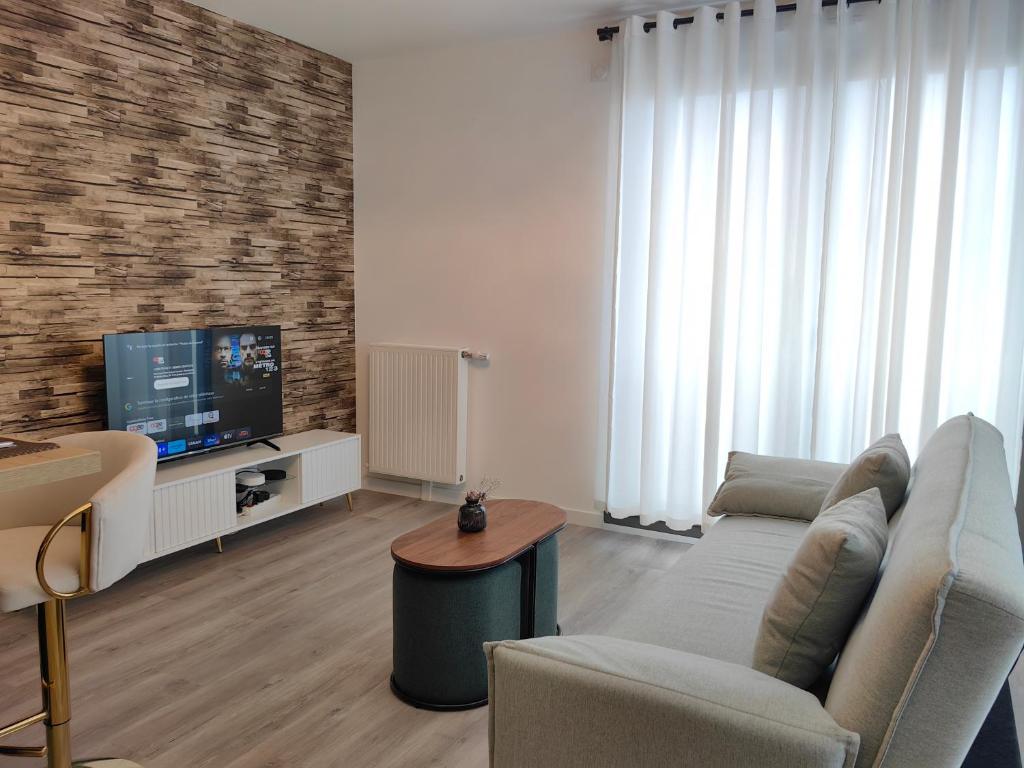 ein Wohnzimmer mit einem Sofa und einem TV in der Unterkunft sacha&#39;s house ,à coté du RER,val d&#39;europe,Paris-Disney . in Bussy-Saint-Georges