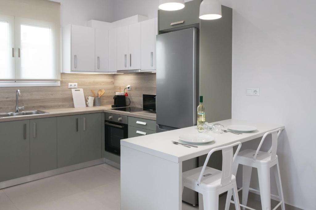 una cocina con armarios blancos y una barra con taburetes en Harmony Luxury Apartment, en Ierápetra