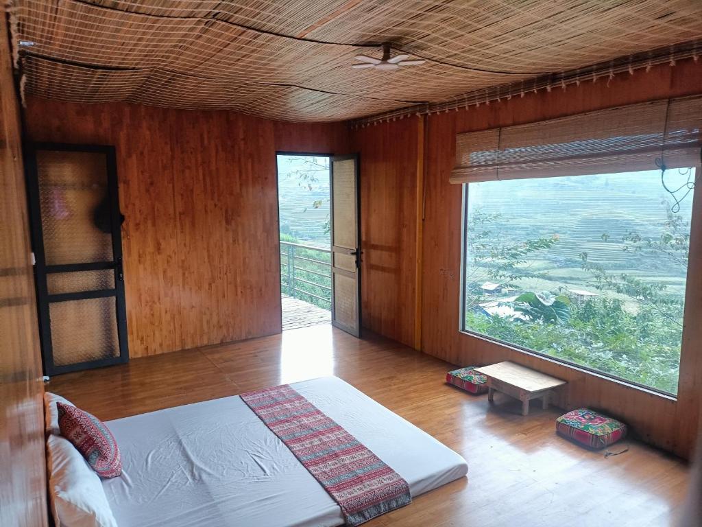 a bedroom with a bed and a large window at Blue home in Mù Cang Chải