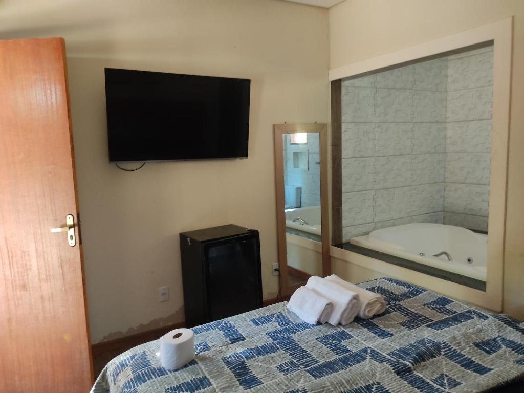 Pousada Rota dos Macacos في نوفا ليما: غرفة نوم مع سرير مع حوض استحمام وتلفزيون