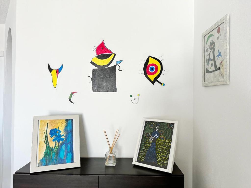 a shelf with two pictures on a white wall with paintings at Relaxing Ocean View, Spacious Art Apartment With Large Terrace, Near Best Costa Adeje Beaches in Adeje