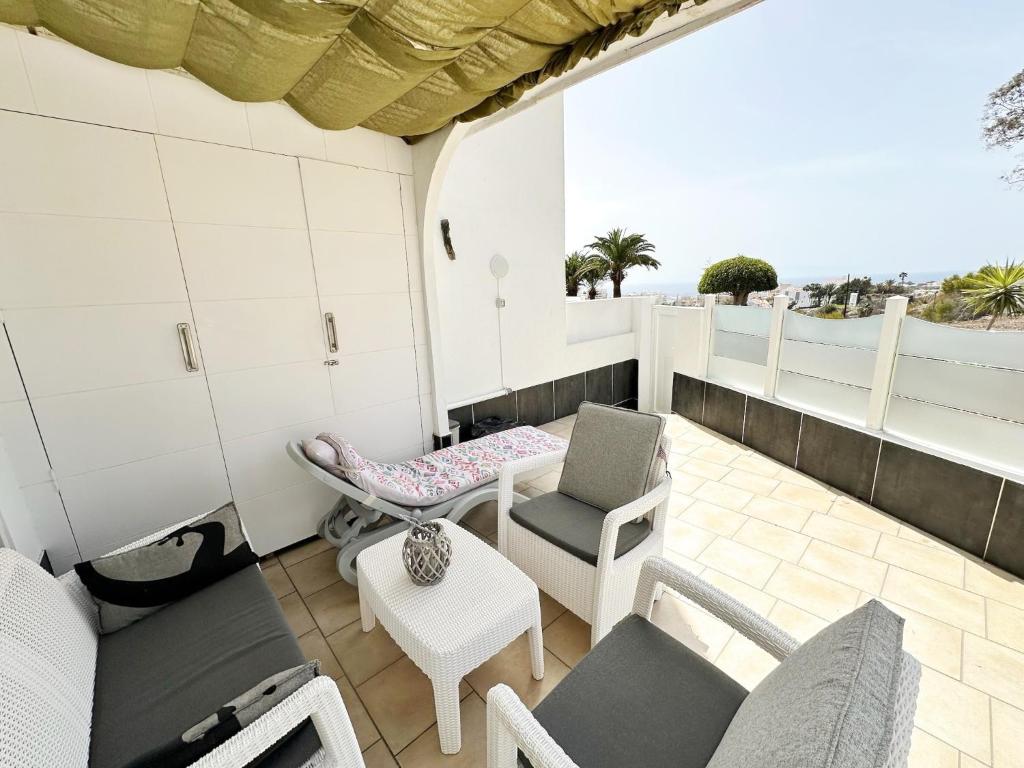 a balcony with chairs and a table and a view of the ocean at Relaxing Ocean View, Spacious Art Apartment With Large Terrace, Near Best Costa Adeje Beaches in Adeje