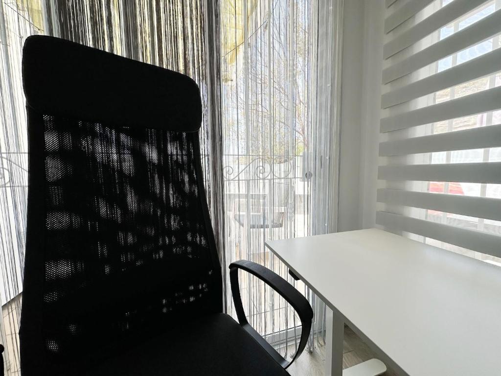 a black chair sitting next to a table and a window at Relaxing Ocean View, Spacious Art Apartment With Large Terrace, Near Best Costa Adeje Beaches in Adeje