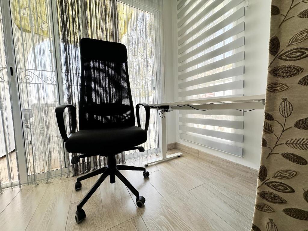 a black office chair sitting in a room with windows at Relaxing Ocean View, Spacious Art Apartment With Large Terrace, Near Best Costa Adeje Beaches in Adeje