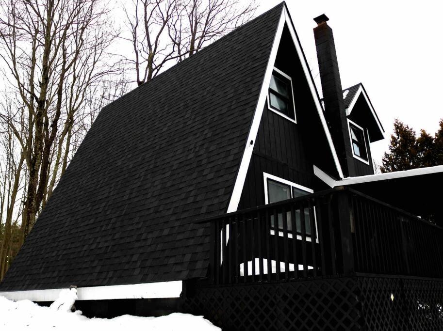 a house with a black roof in the snow at The New Luxury Cabin PetFriendly Pocono Summit in Pocono Summit