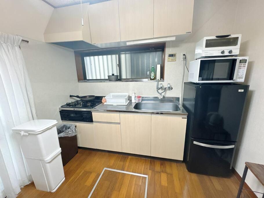 una pequeña cocina con fregadero y microondas en Nana House Ekoda - Private House, en Tokio