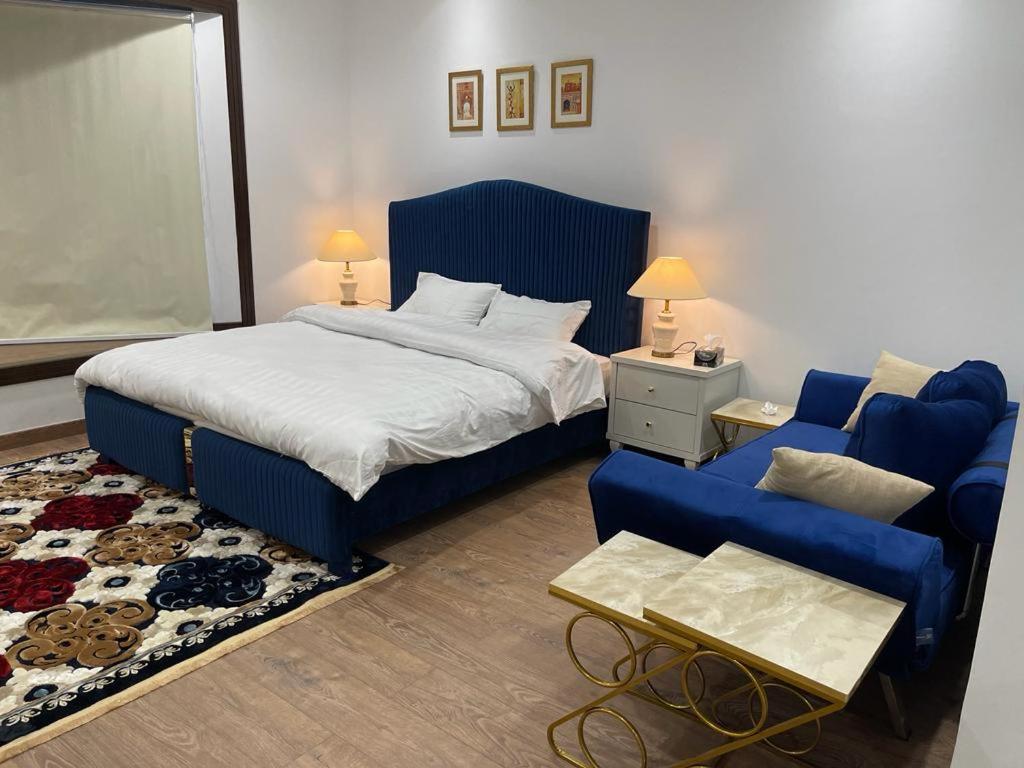 een slaapkamer met een bed en een blauwe bank bij Premium&Cozy Studio DHA Lahore in Lahore