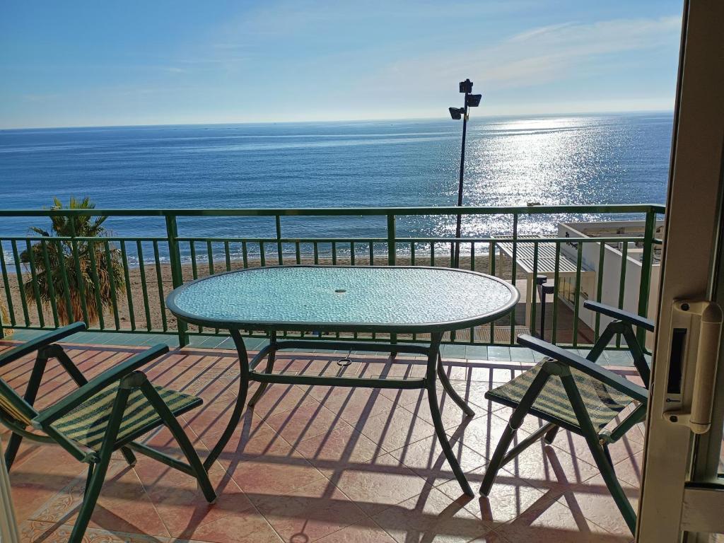 een tafel en stoelen op een balkon met uitzicht op de oceaan bij Fuengirola Primera Línea de Playa in Fuengirola