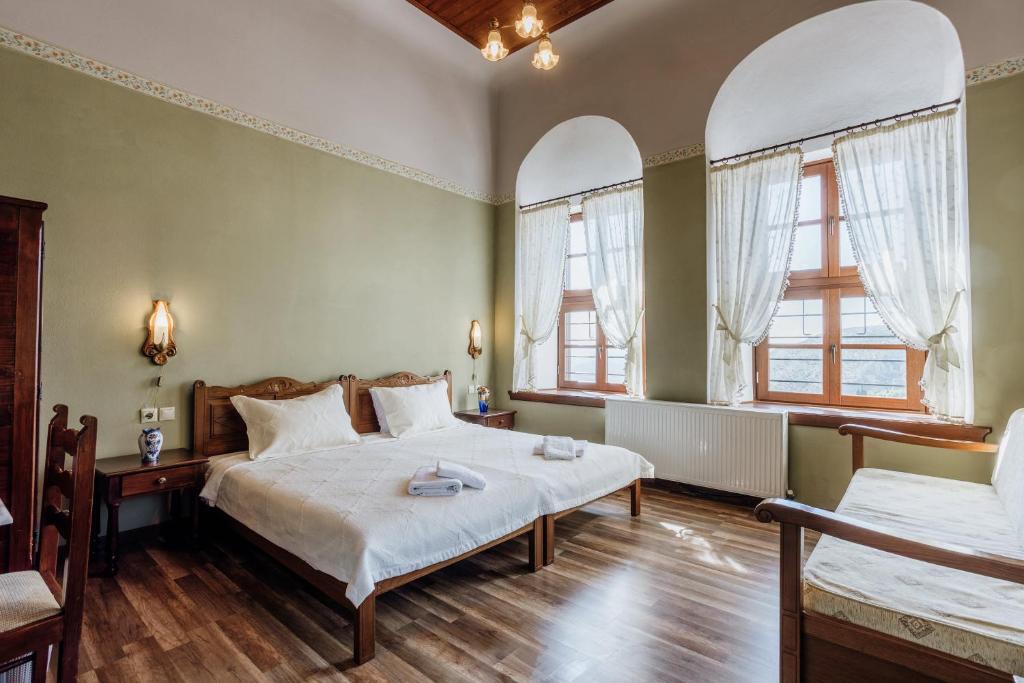 a bedroom with two beds and two windows at Archontiko Kantartzi in Portaria