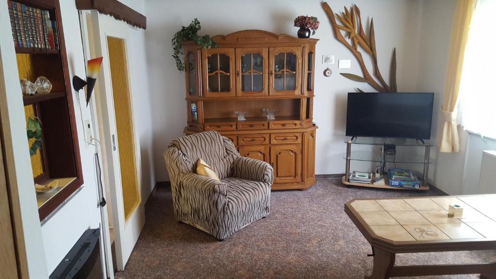 a living room with a cabinet and a chair and a television at Ferienwohnung am Bloschk in Schwielochsee