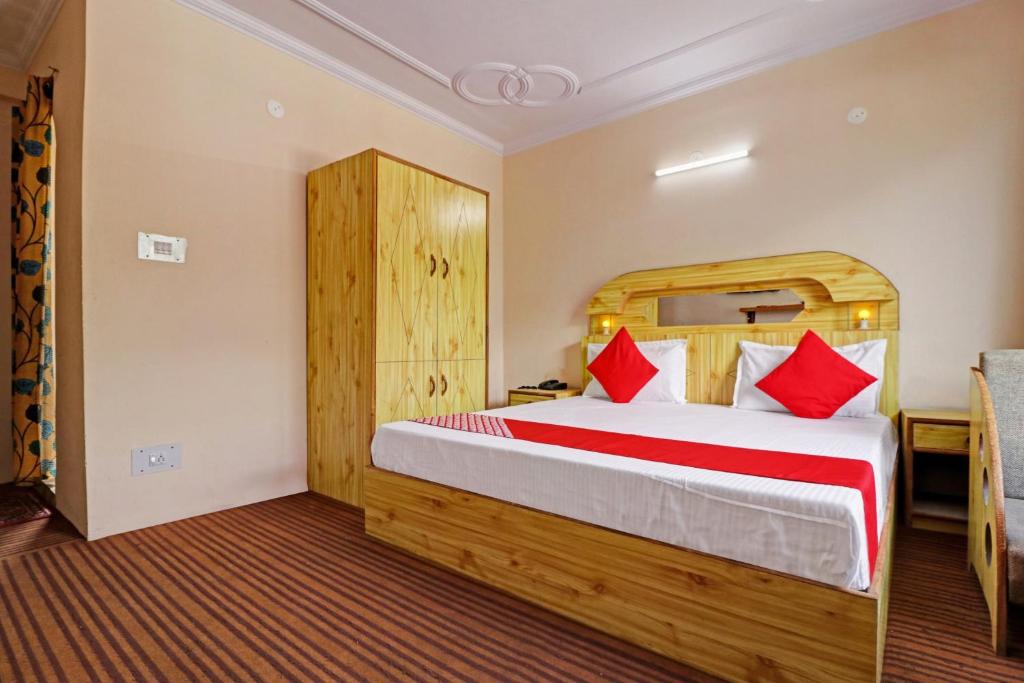 a bedroom with a large bed with red pillows at OYO Flagship Aman Cottage in Manāli