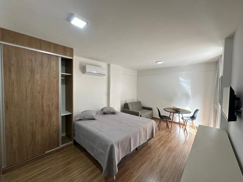 um quarto com uma cama e uma mesa em Studio central com lazer e spa em Poços de Caldas