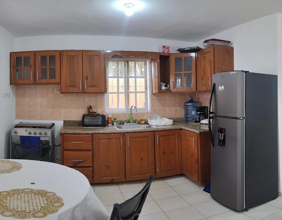 a kitchen with wooden cabinets and a stainless steel refrigerator at Hostal Palmas De Punta Cana in Punta Cana