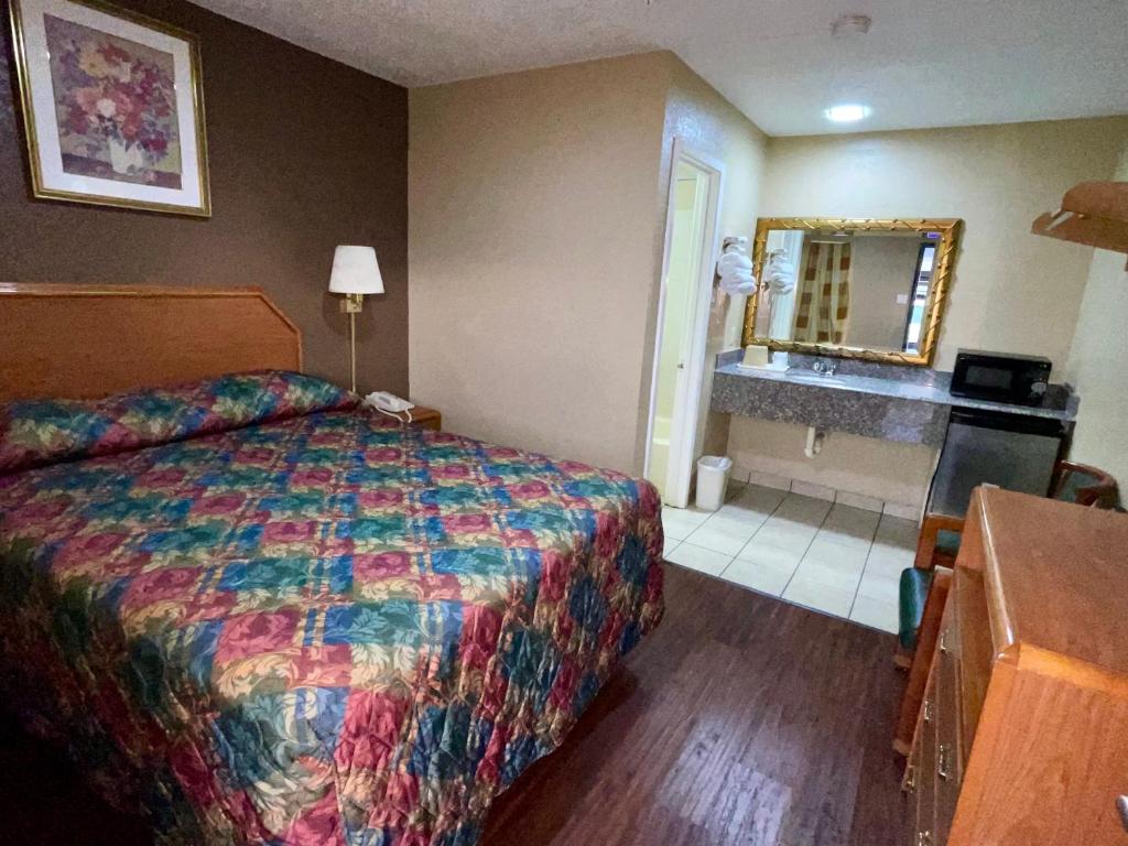 a hotel room with a bed and a bathroom at Ankur Inn Motel in Dallas