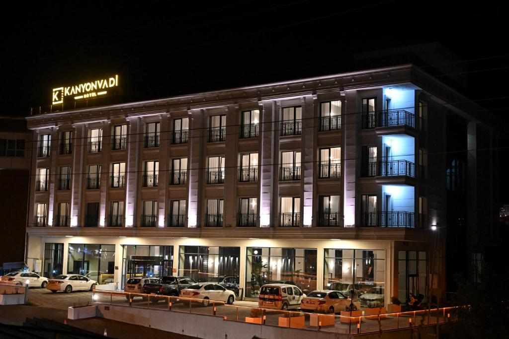 un edificio con coches estacionados fuera de él por la noche en KANYON VADİ HOTEL, en Bostanbükü