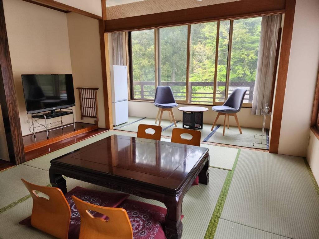 a living room with a table and chairs and a television at 大和屋ホテルいろは in Nikko