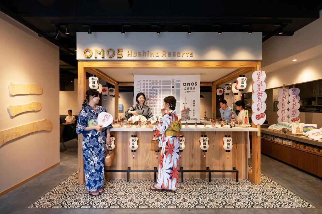 dos mujeres y un niño parados frente a una tienda de sushi en OMO5 Kyoto Sanjo by Hoshino Resorts en Kyoto