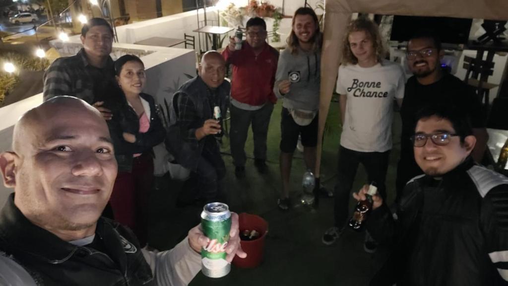 a group of people standing around a man holding a drink at Quinoa Backpackers Hostel in Lima