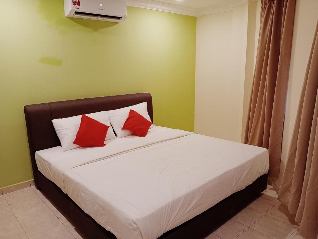 una camera con un letto con due cuscini rossi di HOTEL SAHARA INN TANJUNG MALIM a Kampong Chabang