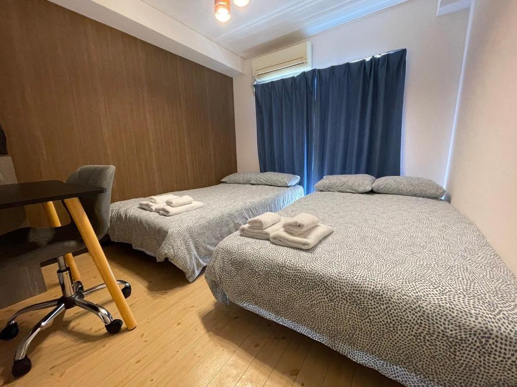 2 camas en una habitación pequeña con cortinas azules en Kurarisu Hakata クラリス博多, en Fukuoka