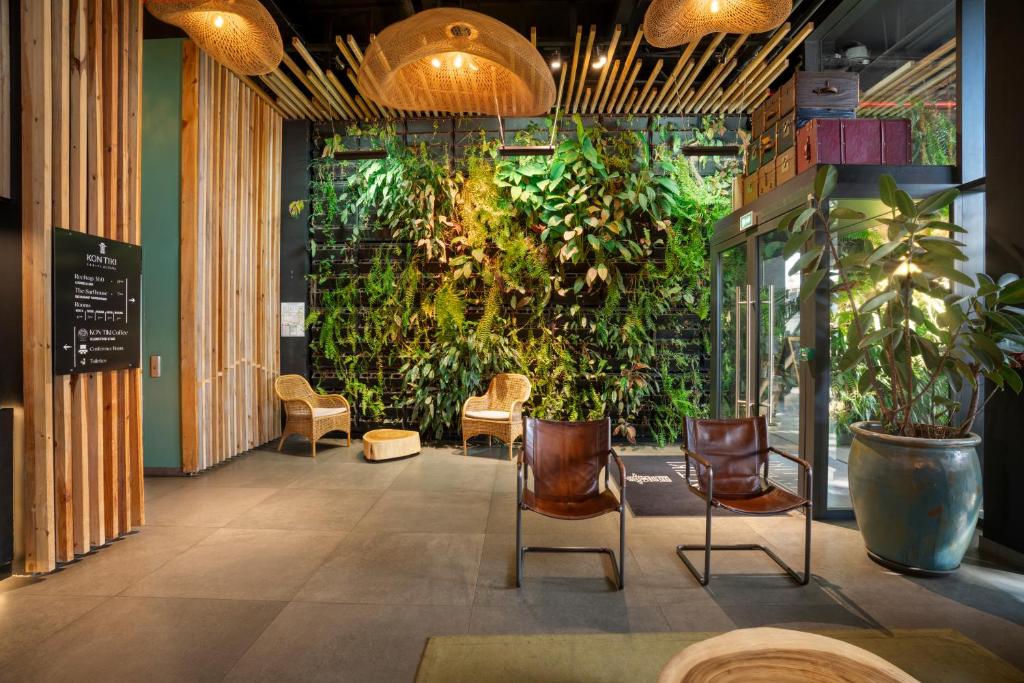 Habitación con una pared verde con sillas y plantas. en Boutique Hôtel Kon Tiki Tahiti en Papeete