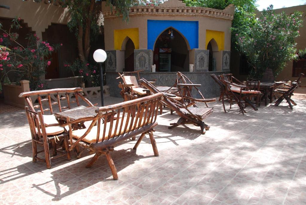 um grupo de cadeiras e mesas de madeira num pátio em Auberge De Charme Les Dunes D´Or em Merzouga