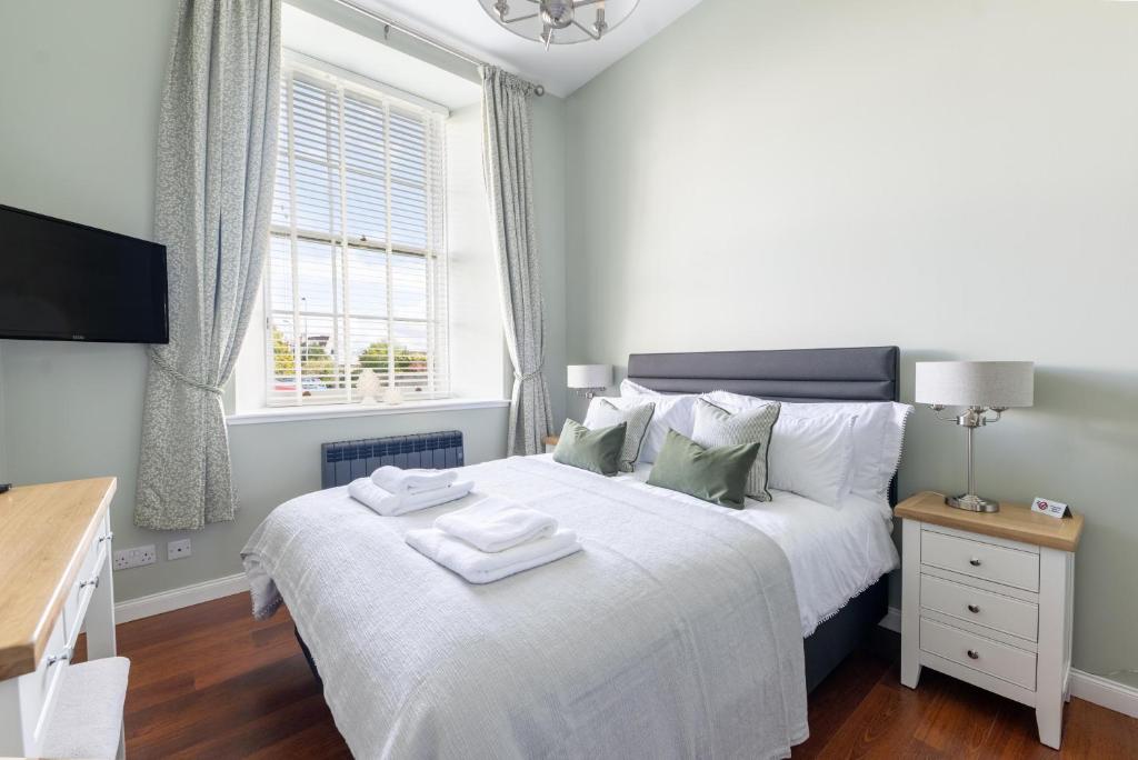 um quarto com uma cama com lençóis brancos e uma janela em 1 Old Edinburgh Court em Inverness