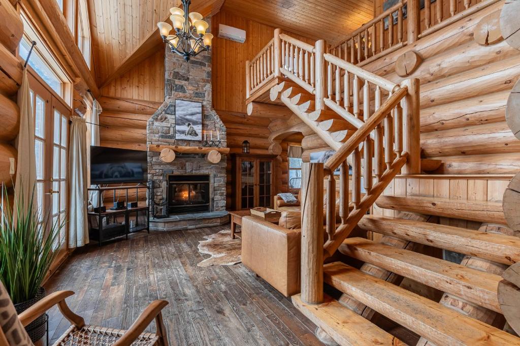 een woonkamer met een houten trap en een open haard bij Fiddler Lake Resort Chalet 10 Ours in Mille-Isles