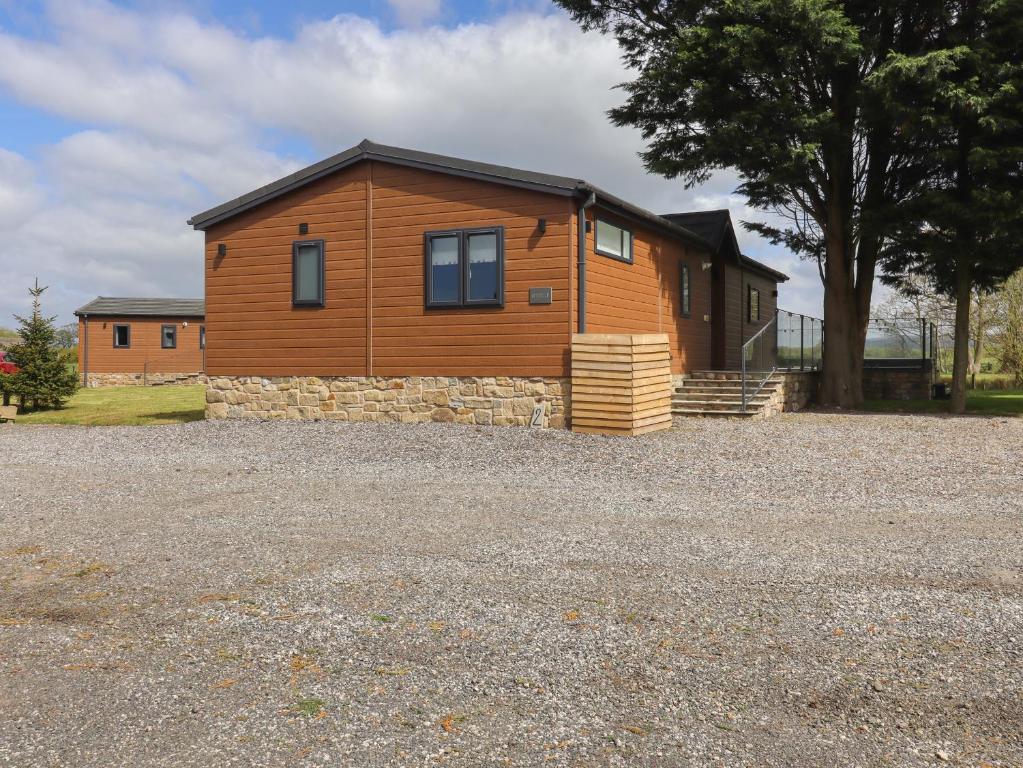 a wooden cabin with a stone wall in front of a house at Ruperts Retreat in Preston