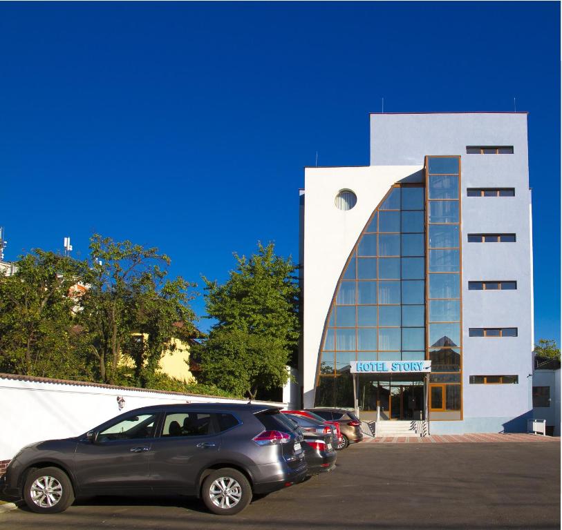 um carro estacionado num parque de estacionamento em frente a um edifício em Hotel Story em Târgu Jiu