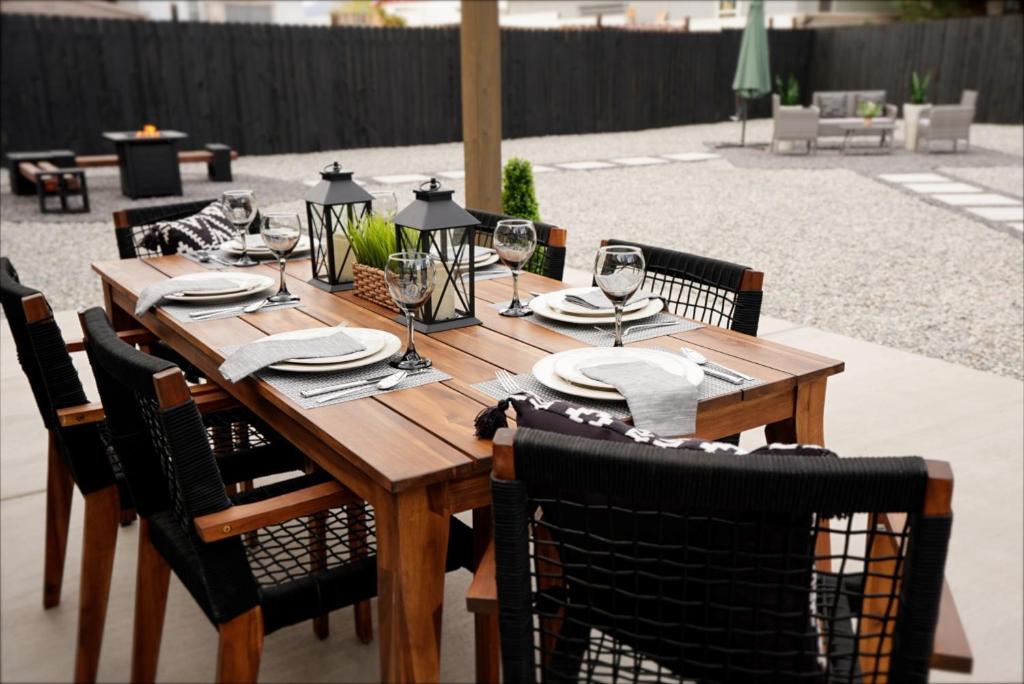 a wooden table with chairs and plates and wine glasses at The White House, A Unique ABQ Stay in Central Location near Uptown in Albuquerque