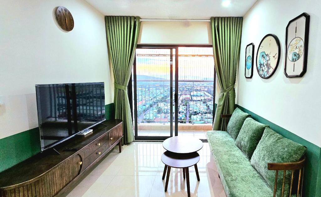 a living room with a green couch and a television at Happy House Quy Nhơn in Quy Nhon
