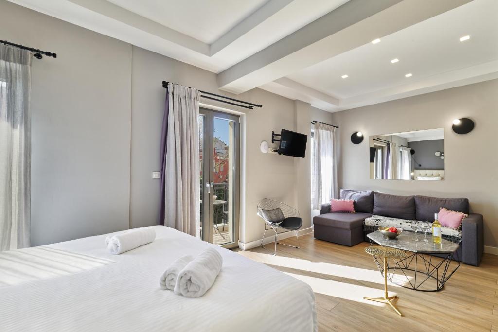 une chambre d'hôtel avec deux lits et un canapé dans l'établissement Nival Luxury Suites, à La Canée