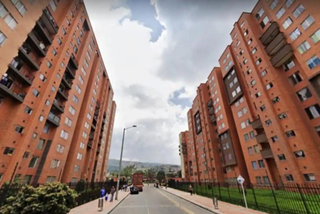 una strada cittadina con due edifici alti e una macchina di Depa Privado en Ambiente Residencial Piscina Gimnacio a Bogotá