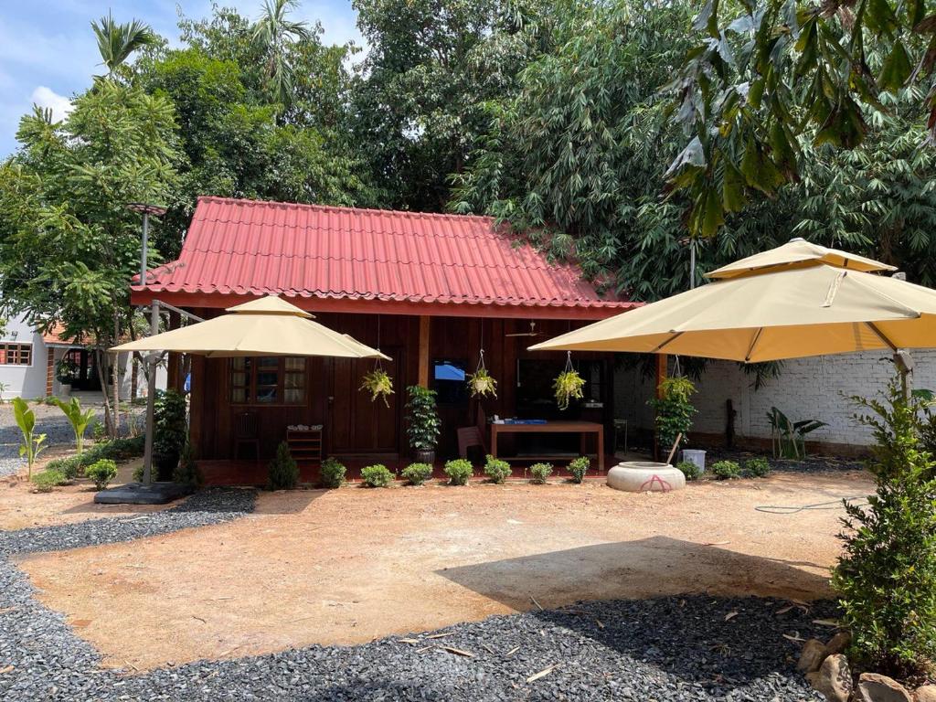 a building with two umbrellas in front of it at Wooden house 2 Beds 1 BR 1KCH 1 Dinning Area in Kampot