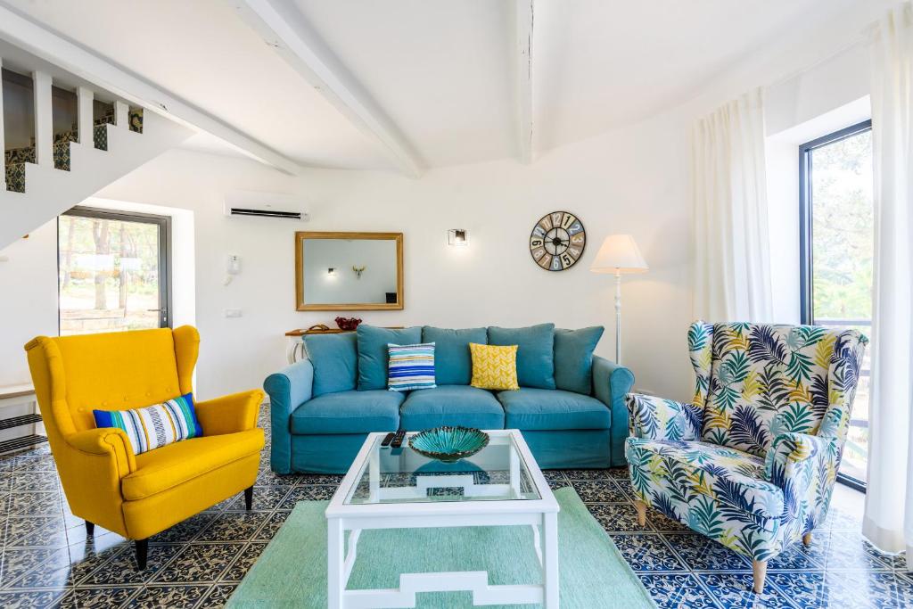 uma sala de estar com um sofá azul e duas cadeiras em Casa dos Sonhos no Vale do Lobo