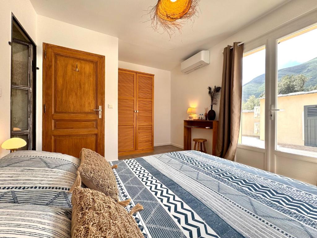 a bedroom with a bed and a large window at Les 5 Arches in Sisco