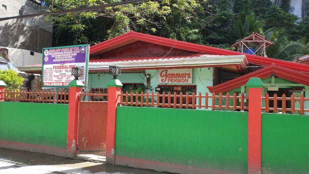 un petit bâtiment vert et rouge avec un panneau dans l'établissement Jammers Pension House, à El Nido